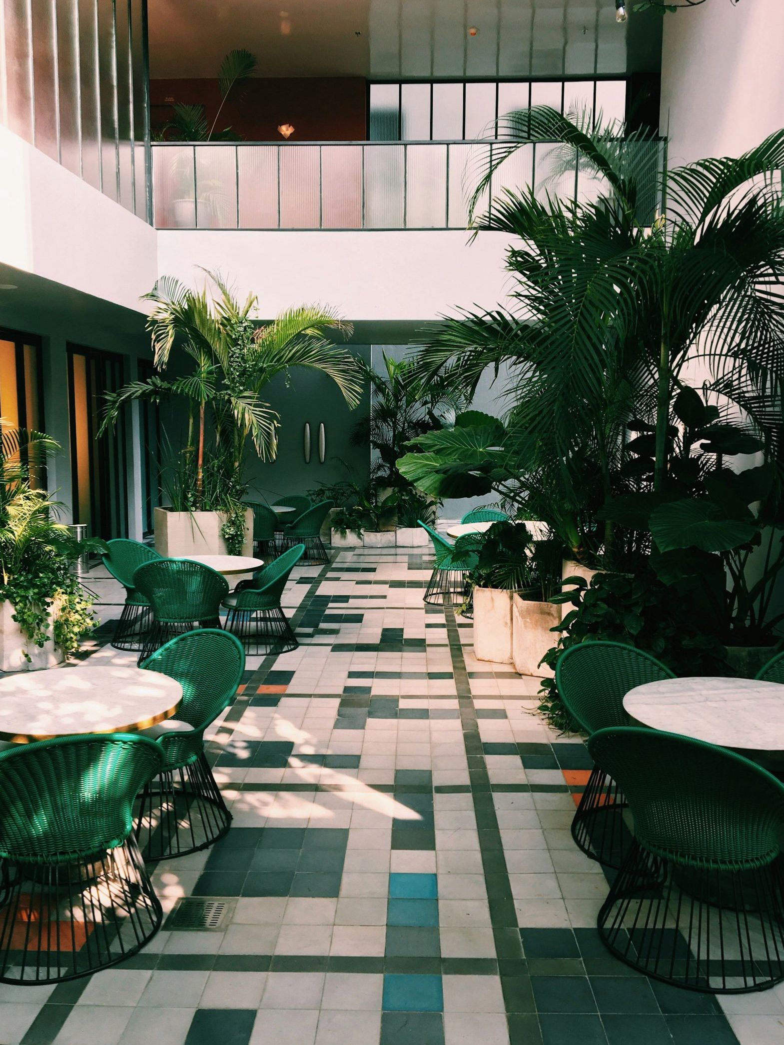 Atrium lobby with tiered balconies, greenery and a patterned floor