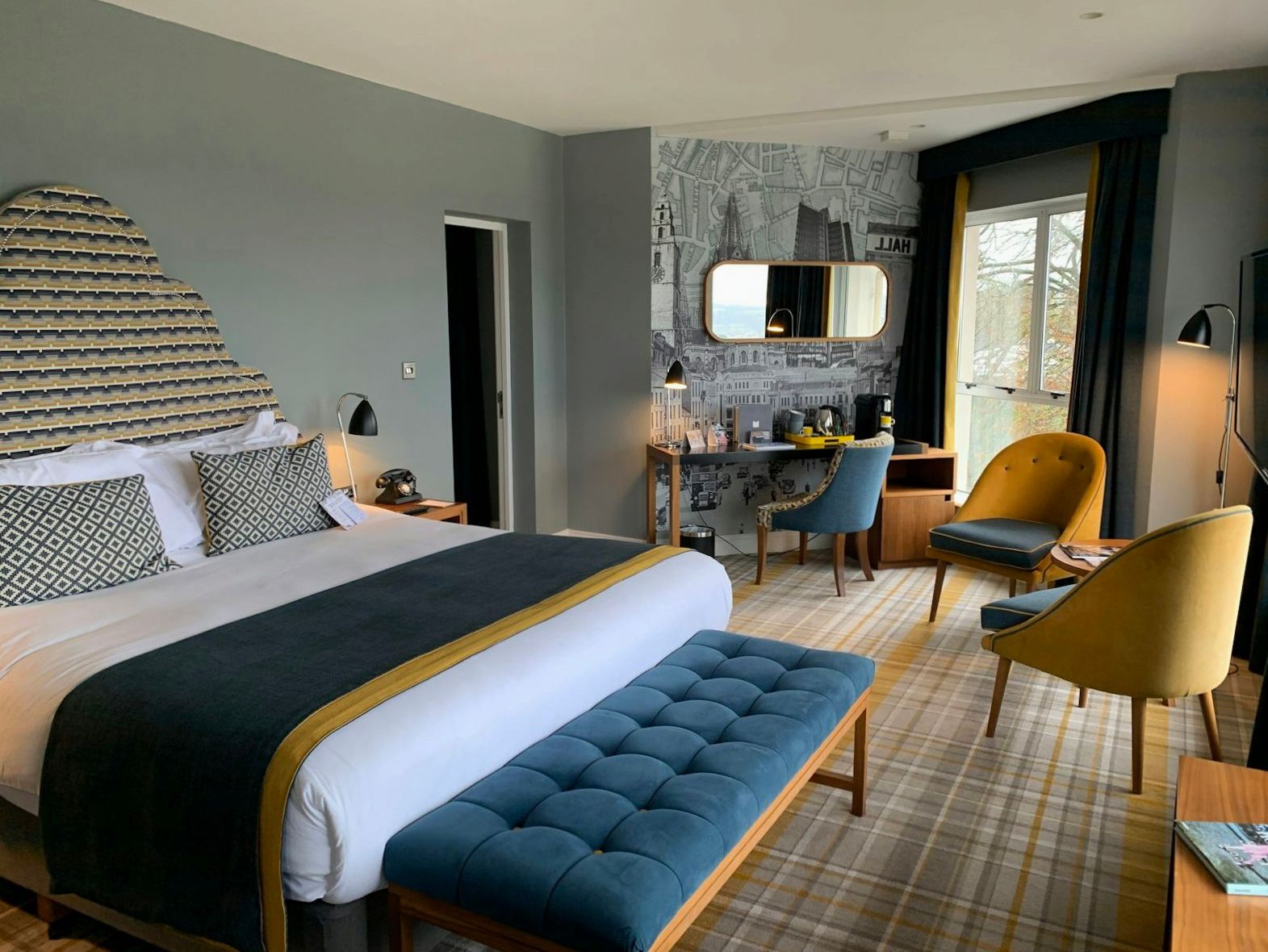 Contemporary deluxe guest room with king bed, upholstered bench and workspace