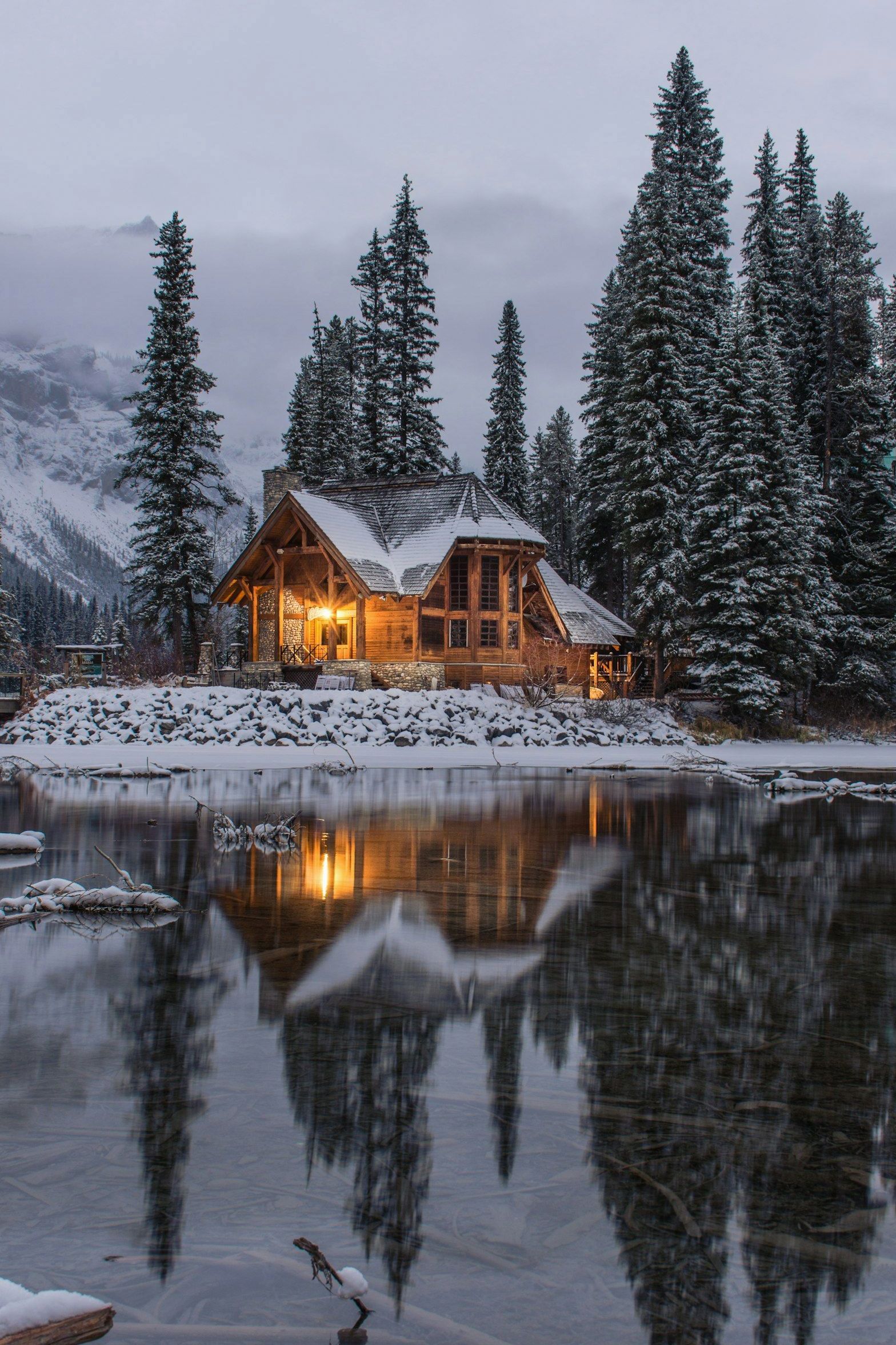 Snow-covered lodge of the Rewardcodecenter property beside a frozen lake at blue hour